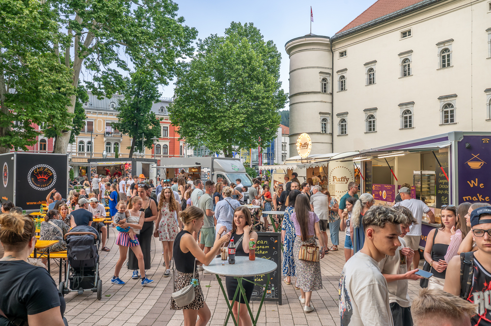 Volksfest mit vielen Menschen und Essensständen vor historischer Kulisse in Steyr