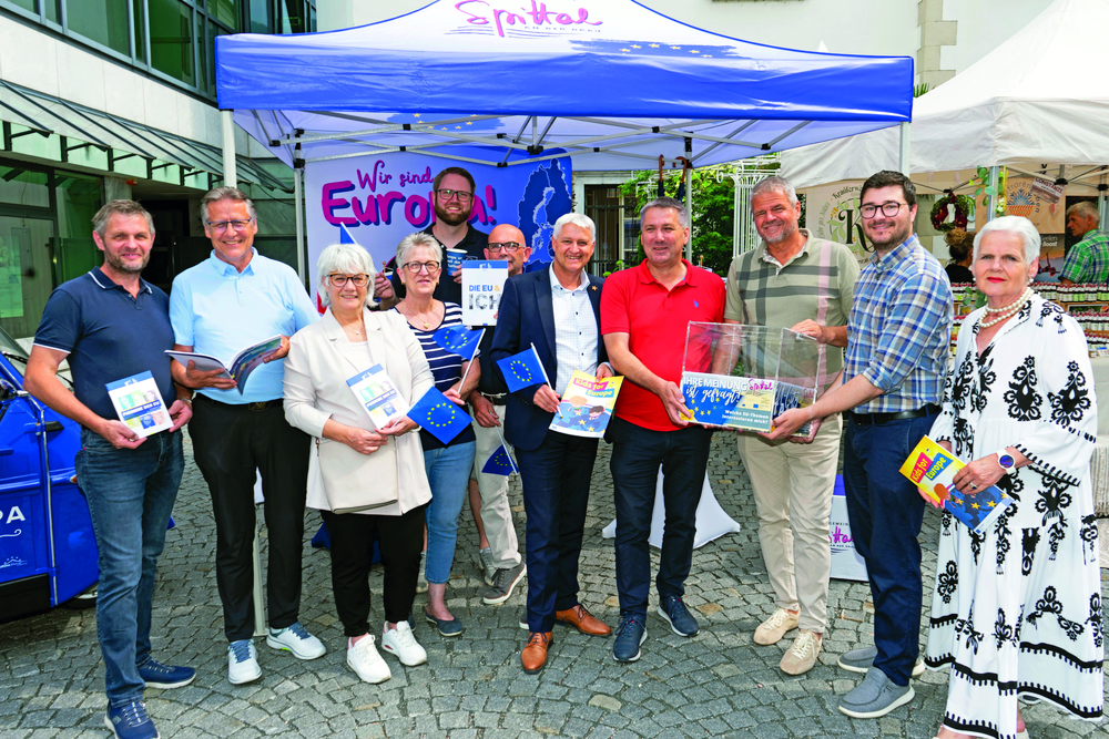 Menschen mit EU-Fahnen und Broschüren vor einem Zelt mit der Aufschrift "Wir sind Europa!"